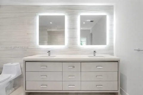 a bathroom with a granite countertop sink vanity mirror and a toilet