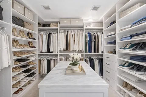 a view of walk in closet with clothes and shoes