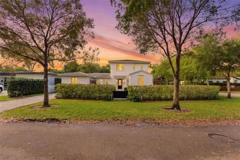 a front view of a house with a garden and trees