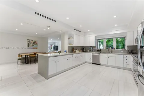 a large white kitchen with lots of counter space a sink appliances and cabinets