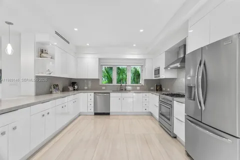 a kitchen with white cabinets stainless steel appliances a sink and a window