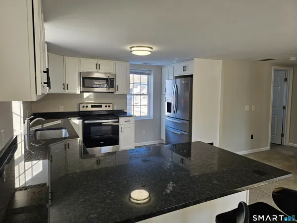 a kitchen with stainless steel appliances granite countertop a stove a sink and a refrigerator