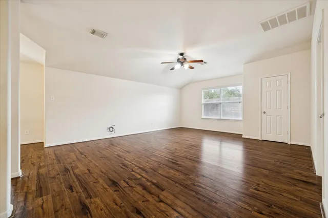 an empty room with wooden floor and chandelier fan
