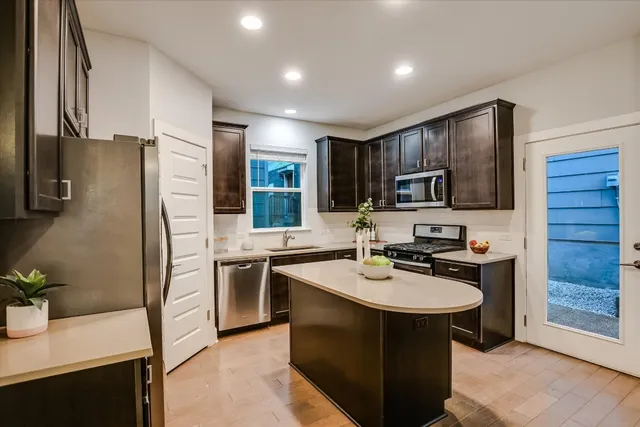 a kitchen with stainless steel appliances granite countertop a sink stove refrigerator and cabinets