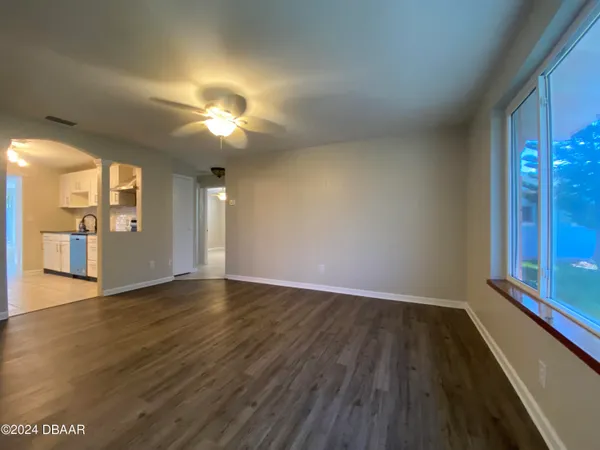 a view of an empty room with window and wooden floor