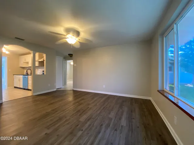 a view of an empty room with window and wooden floor