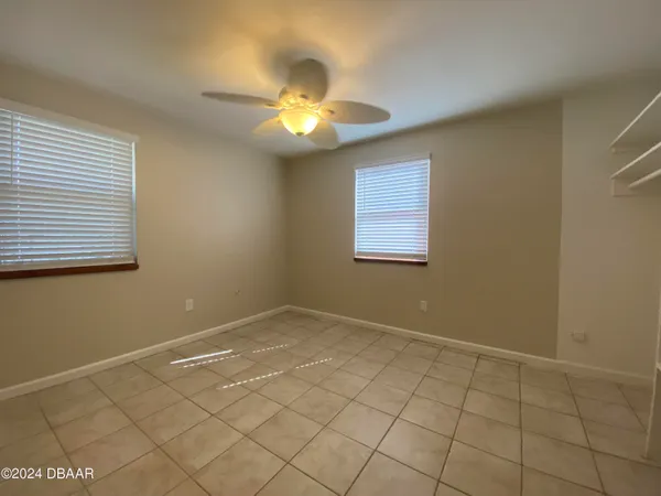 an empty room with windows and fan