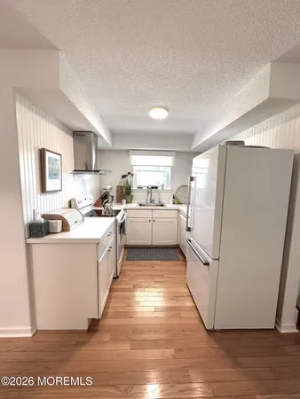 a large white open refrigerator a sink a dishwasher a dining table and chairs