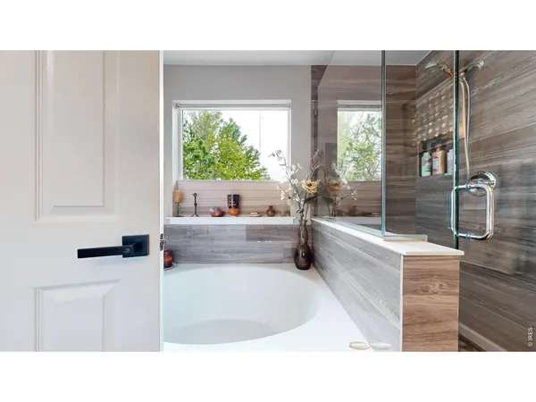 a bathroom with a tub a sink and a large window