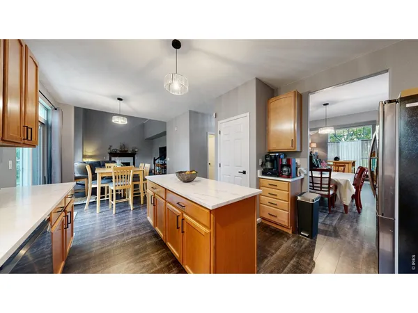 a living room with stainless steel appliances kitchen island granite countertop a table chairs and a refrigerator