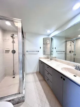 a bathroom with a double vanity sink toilet mirror and shower