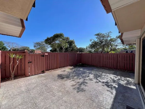 a view of backyard with wooden fence and trees in the background