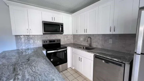 a kitchen with stainless steel appliances granite countertop a stove a microwave and a sink