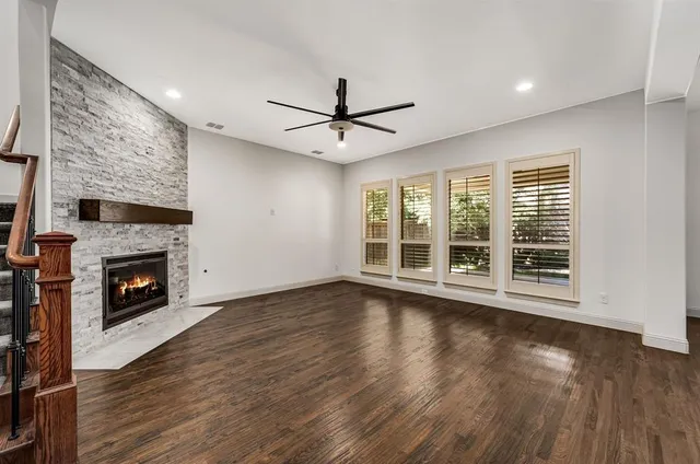 a view of an empty room with wooden floor and a fireplace