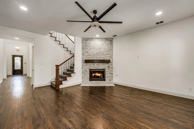 an empty room with wooden floor a ceiling fan and a fireplace
