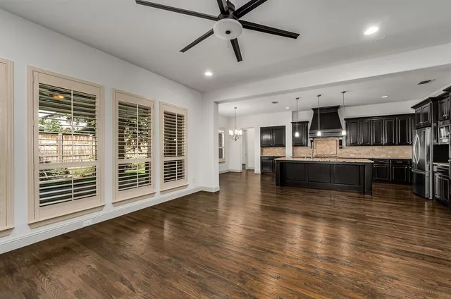 a living room with stainless steel appliances kitchen island granite countertop a large window and a kitchen view