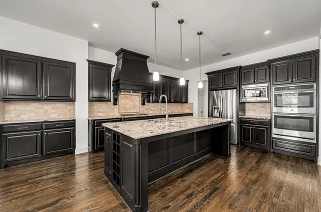 a kitchen with stainless steel appliances kitchen island granite countertop a stove and a refrigerator