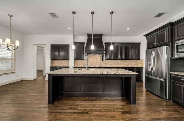 a kitchen with stainless steel appliances granite countertop a refrigerator a stove and a sink with wooden floor