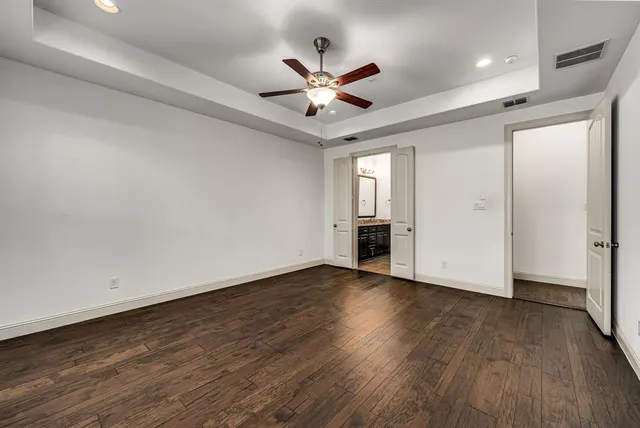 a view of an empty room with wooden floor and a ceiling fan