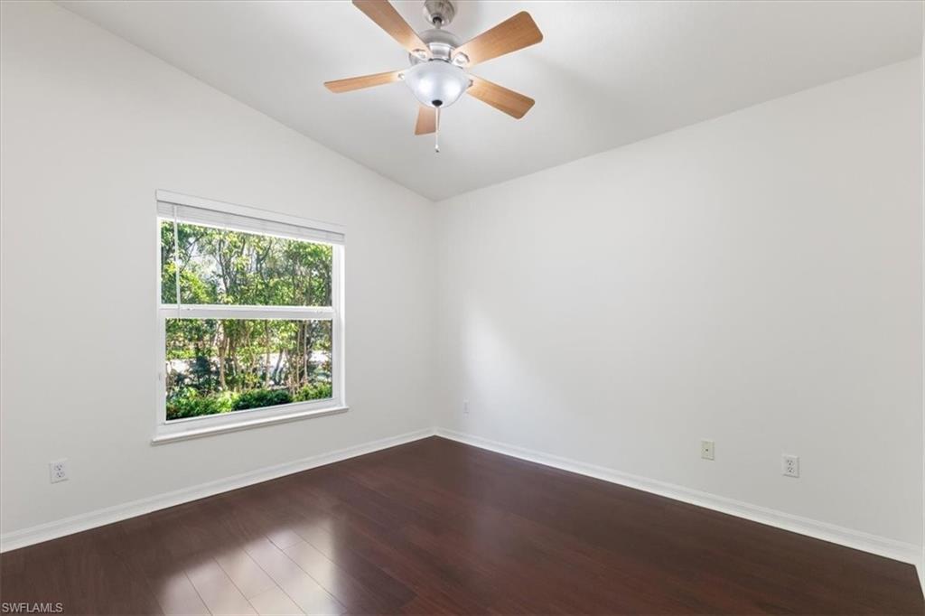 15073 Cortona Way Naples, FL 34120 - Photo 11 of 35 an empty room with wooden floor fan and windows