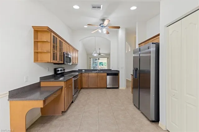 a kitchen with stainless steel appliances a refrigerator a sink a stove top oven a washer dryer and cabinets