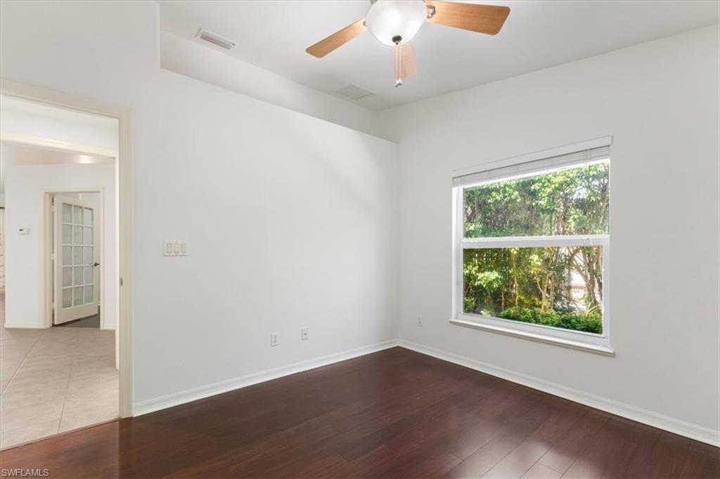 15073 Cortona Way Naples, FL 34120 - Photo 10 of 35 an empty room with wooden floor and windows