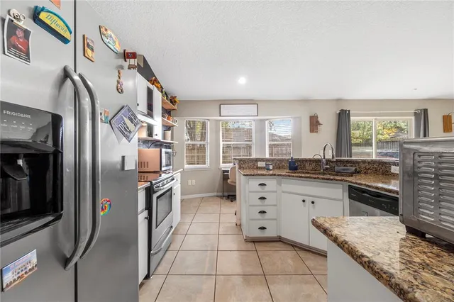 a kitchen with stainless steel appliances granite countertop a refrigerator a stove and a sink with cabinets