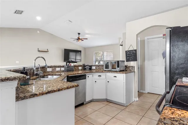 a kitchen with granite countertop a sink appliances cabinets and furniture