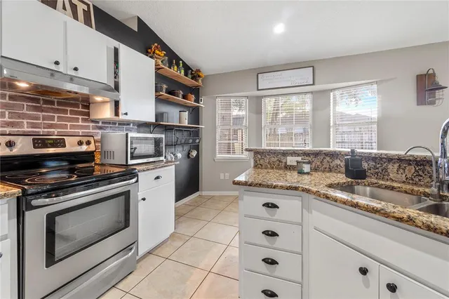 a kitchen with stainless steel appliances granite countertop a stove sink and cabinets