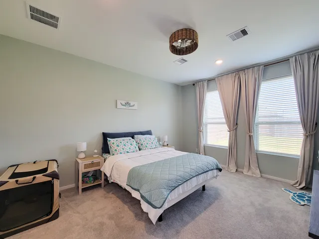 a spacious bedroom with a bed and a flat screen tv