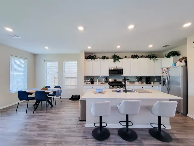 a large kitchen with stainless steel appliances granite countertop a lot of counter space a sink and dishwasher a stove top oven with wooden floor