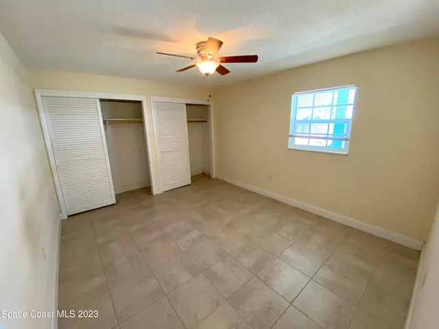 an empty room with closet and a ceiling fan