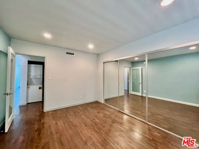 a view of an empty room with wooden floor and closet