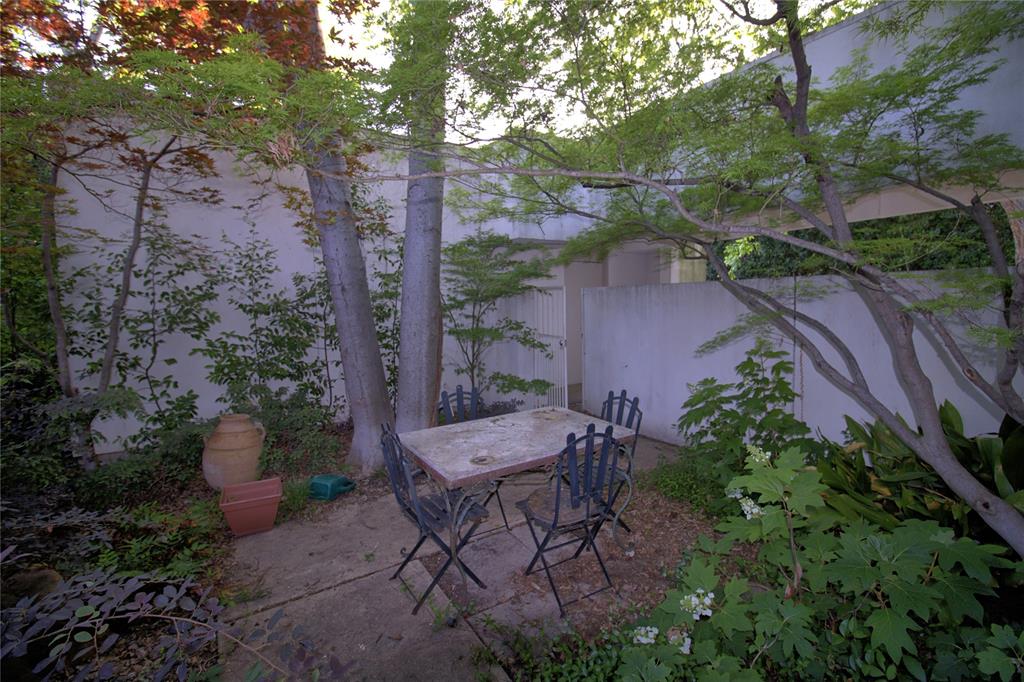 5108 Maple Springs Boulevard Dallas, TX 75235 - Photo 36 of 39 a view of a backyard with plants and a lawn chairs under an umbrella