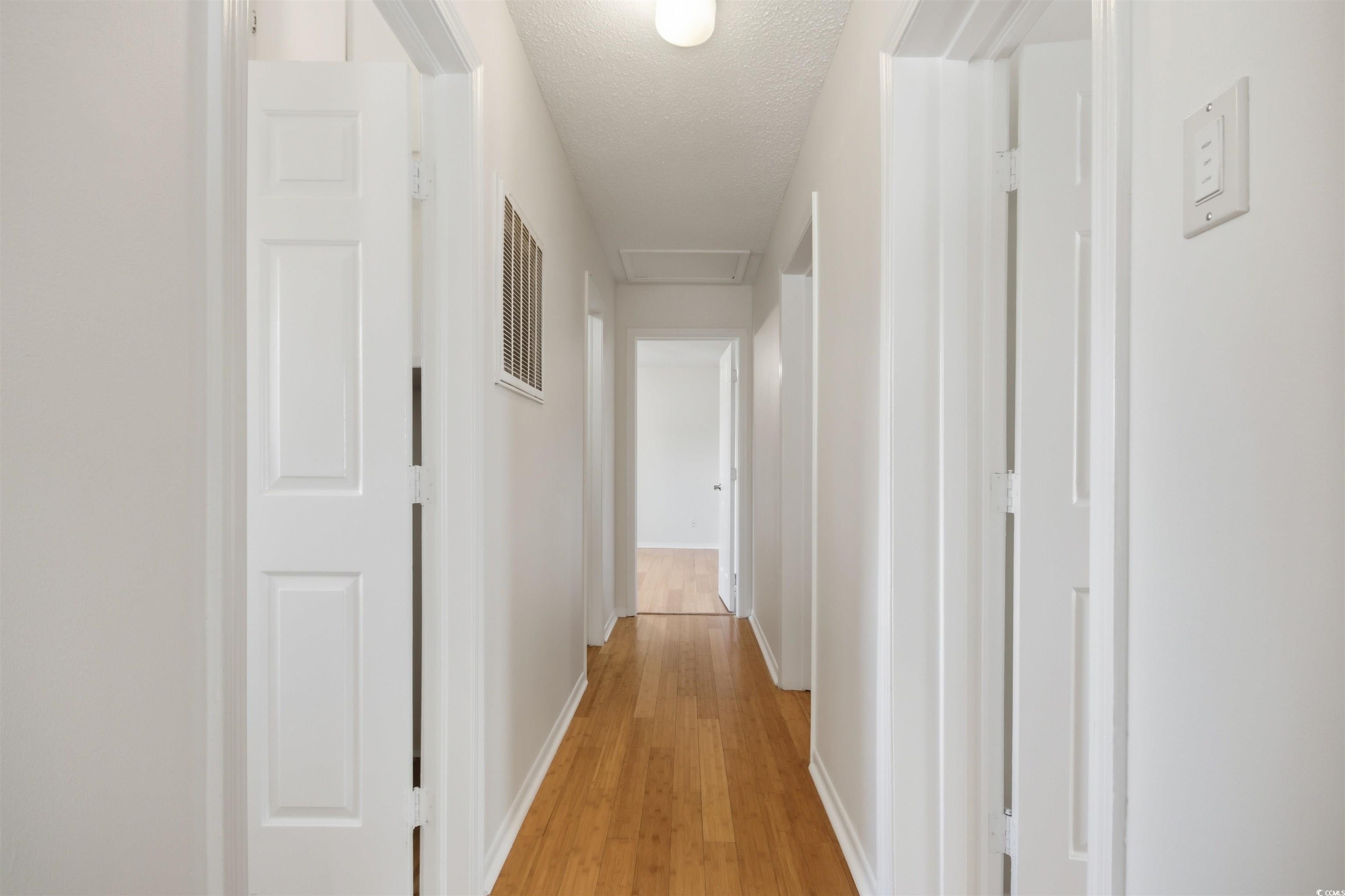 462 Bay Drive Murrells Inlet, SC 29576 - Photo 4 of 37 Hallway with light wood-style flooring, attic access, and a textured ceiling