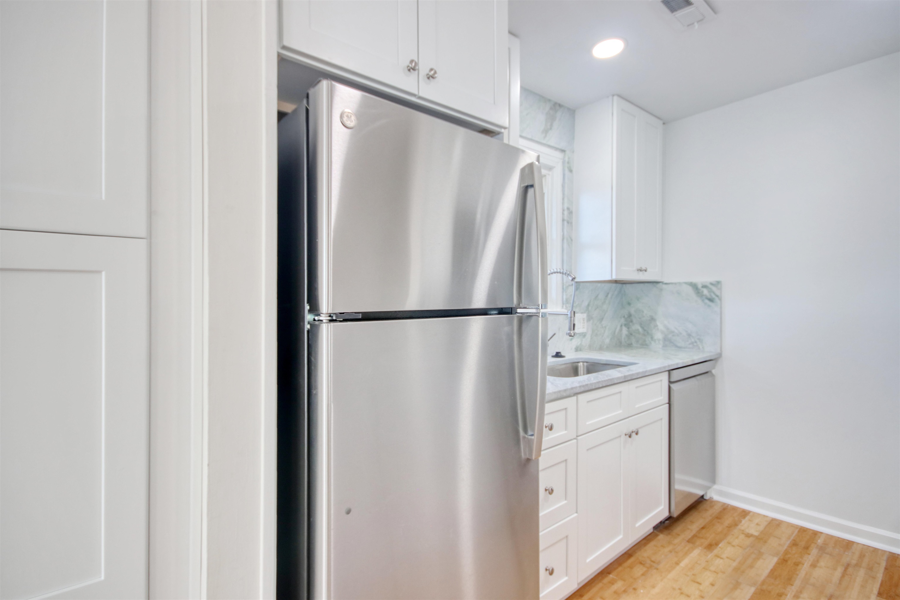 462 Bay Drive Murrells Inlet, SC 29576 - Photo 6 of 37 Kitchen featuring stainless steel appliances, light wood-type flooring, white cabinetry, a peninsula, and tasteful backsplash