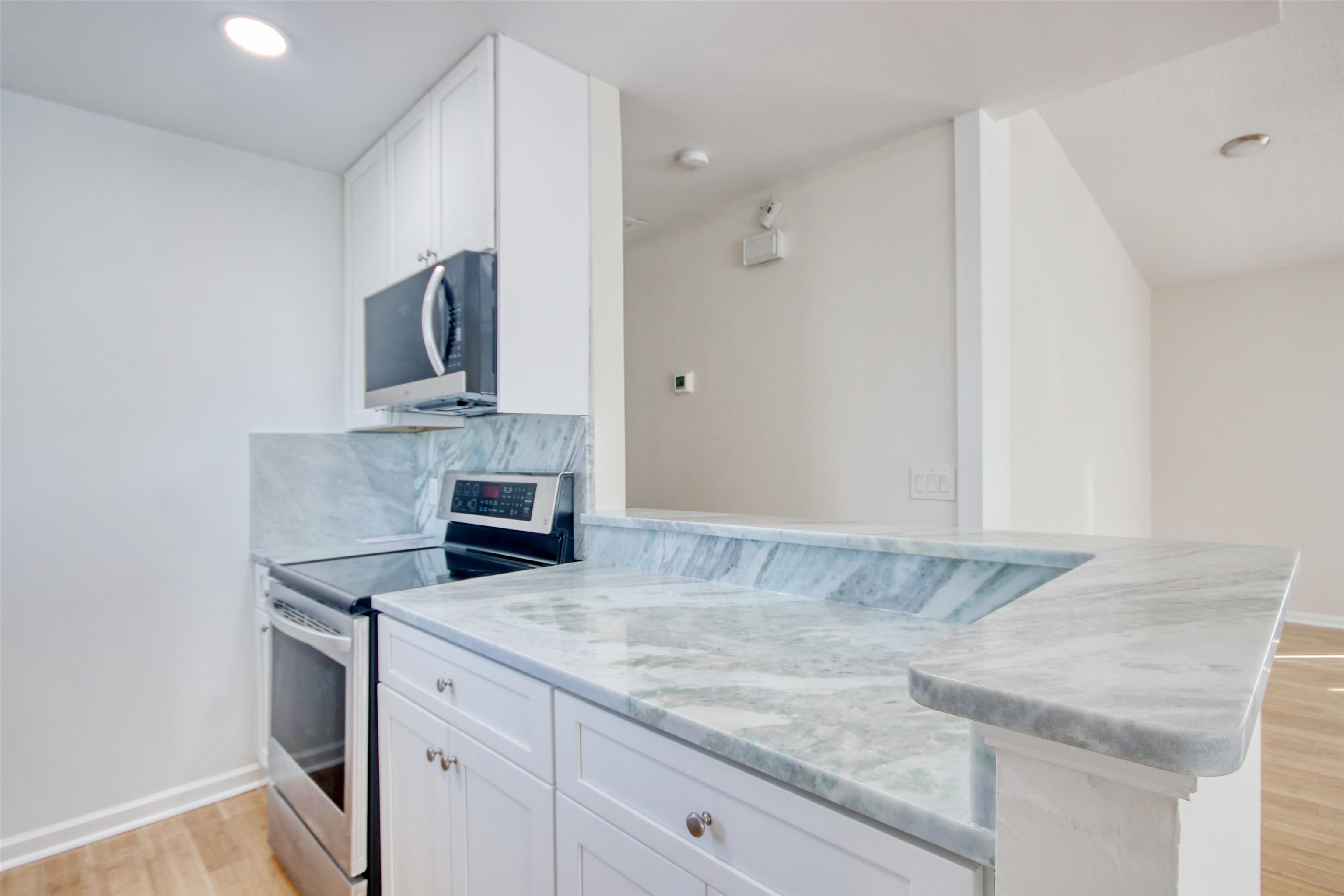 462 Bay Drive Murrells Inlet, SC 29576 - Photo 7 of 37 Kitchen with stainless steel appliances, white cabinetry, light wood finished floors, light stone countertops, and decorative backsplash
