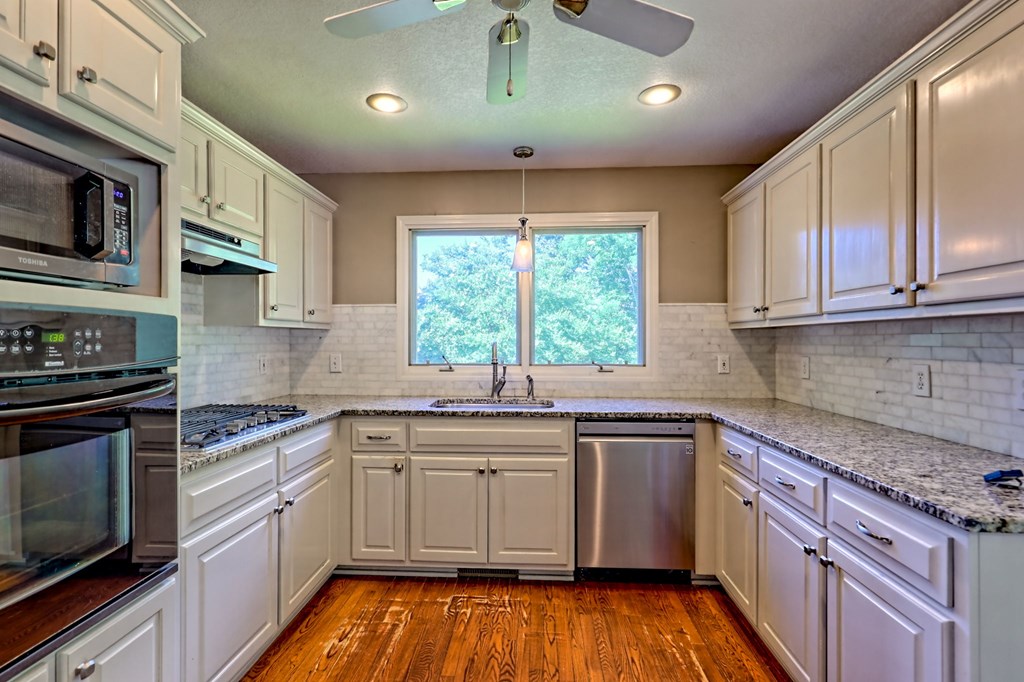 136 Elf School Road Hayesville, NC 28904 - Photo 30 of 84 a kitchen with stainless steel appliances granite countertop wooden cabinets stove a sink and dishwasher next to a window