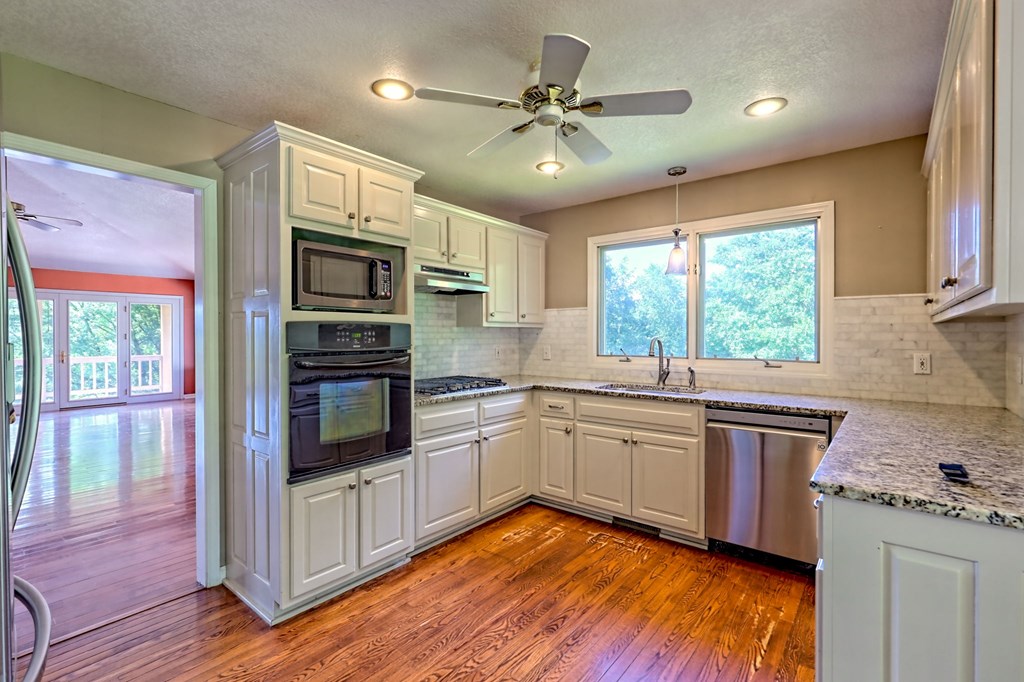 136 Elf School Road Hayesville, NC 28904 - Photo 31 of 84 a kitchen with stainless steel appliances granite countertop hardwood floor sink stove and wooden cabinets
