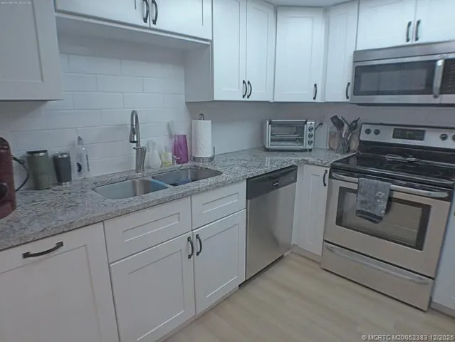 a kitchen with granite countertop white cabinets and a stove