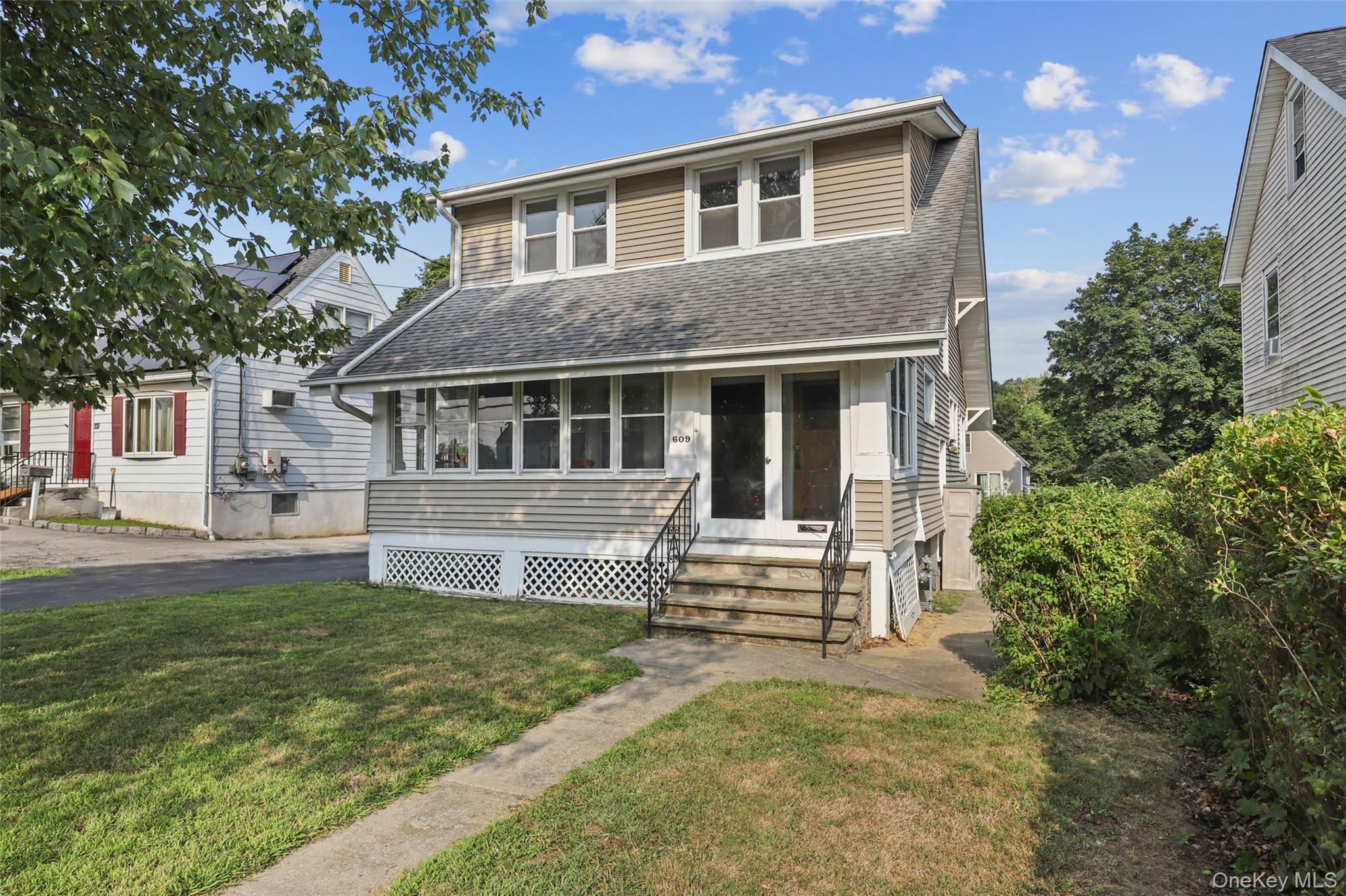 View of front of home featuring entry steps, a shingled roof, and a front lawn