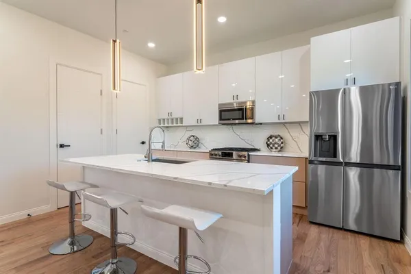 a kitchen with a sink a refrigerator a stove and white cabinets with wooden floor