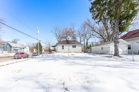 a view of a white house with a yard covered in snow