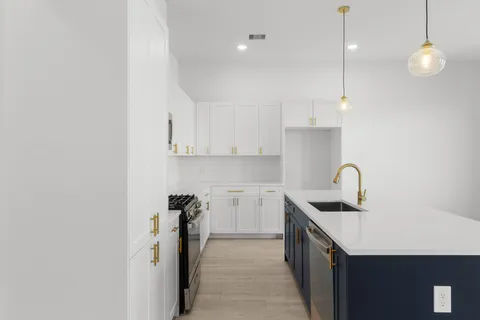a kitchen with a sink dishwasher and a stove with wooden floor