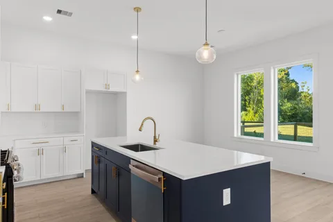 a kitchen with a stove a sink a window and cabinets