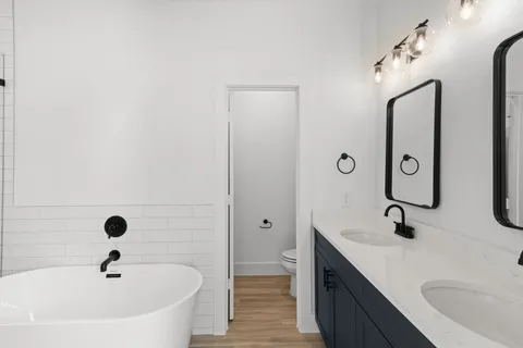 a bathroom with a tub sink double vanity and mirror