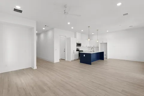 a large room with kitchen island a sink wooden floor and chandelier
