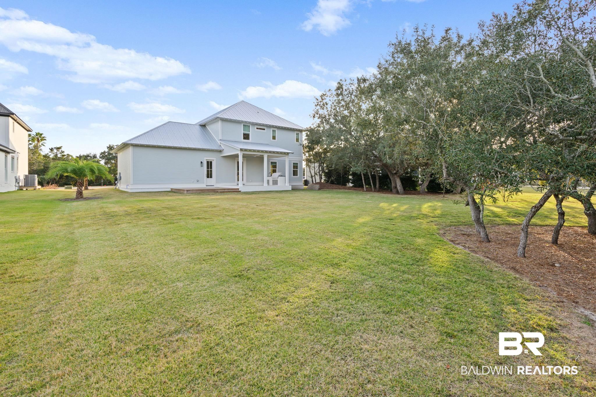 30313 River Road Orange Beach, AL 36561 - Photo 11 of 50 Rear view of house featuring a yard, a metal roof, and a patio area