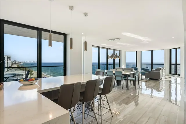 a living room with stainless steel appliances kitchen island granite countertop a table chairs and a view of living room