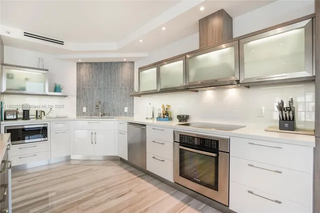a kitchen with cabinets wooden floor and stainless steel appliances